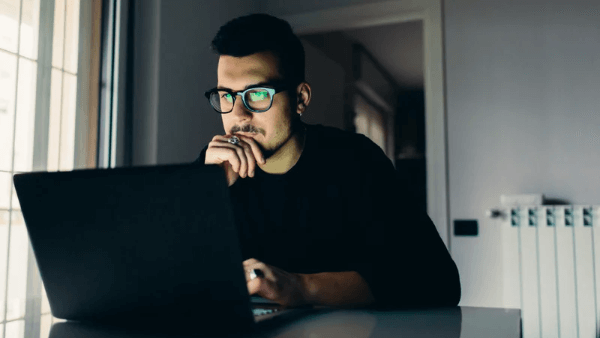 homem de preto pensando em frente a um laptop