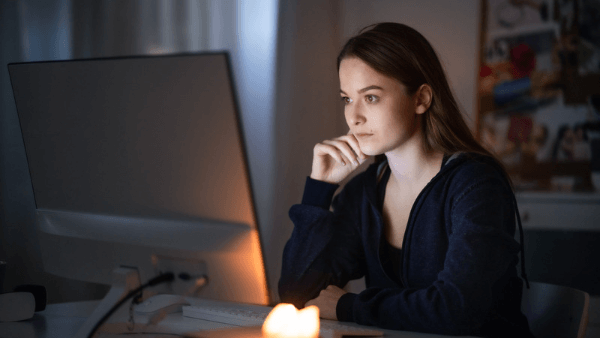 mulher pensativa em frente a tela de um computador