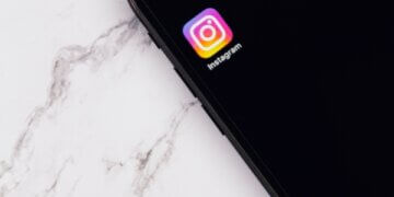 celular com fundo preto e logo do instagram na tela